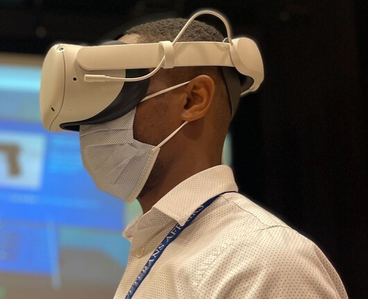 a person wearing a VR headset, weraing a mask, and a Veterans Affairs lanyard