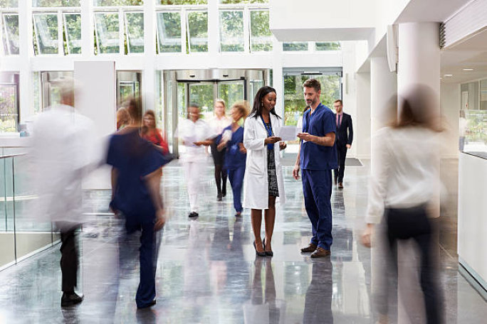 a doctor and medical staff speaking in a busy hallway